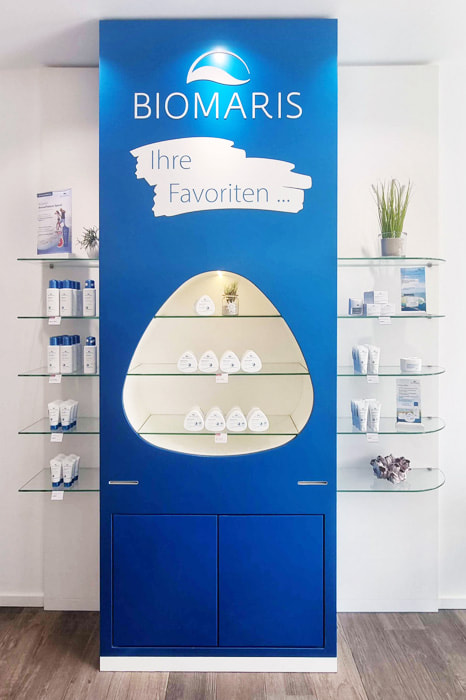 BIOMARIS Shop Travemünde Präsentationswand in Blau mit BIOMARIS Favourites Produkten und Glasregalen mit Pflegeprodukten