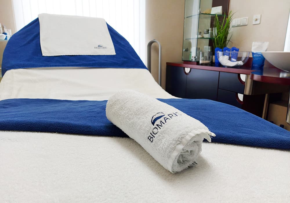 BIOMARIS Kosmetik-Institut Liege mit blau-weißer Auflage und gerolltem Handtuch