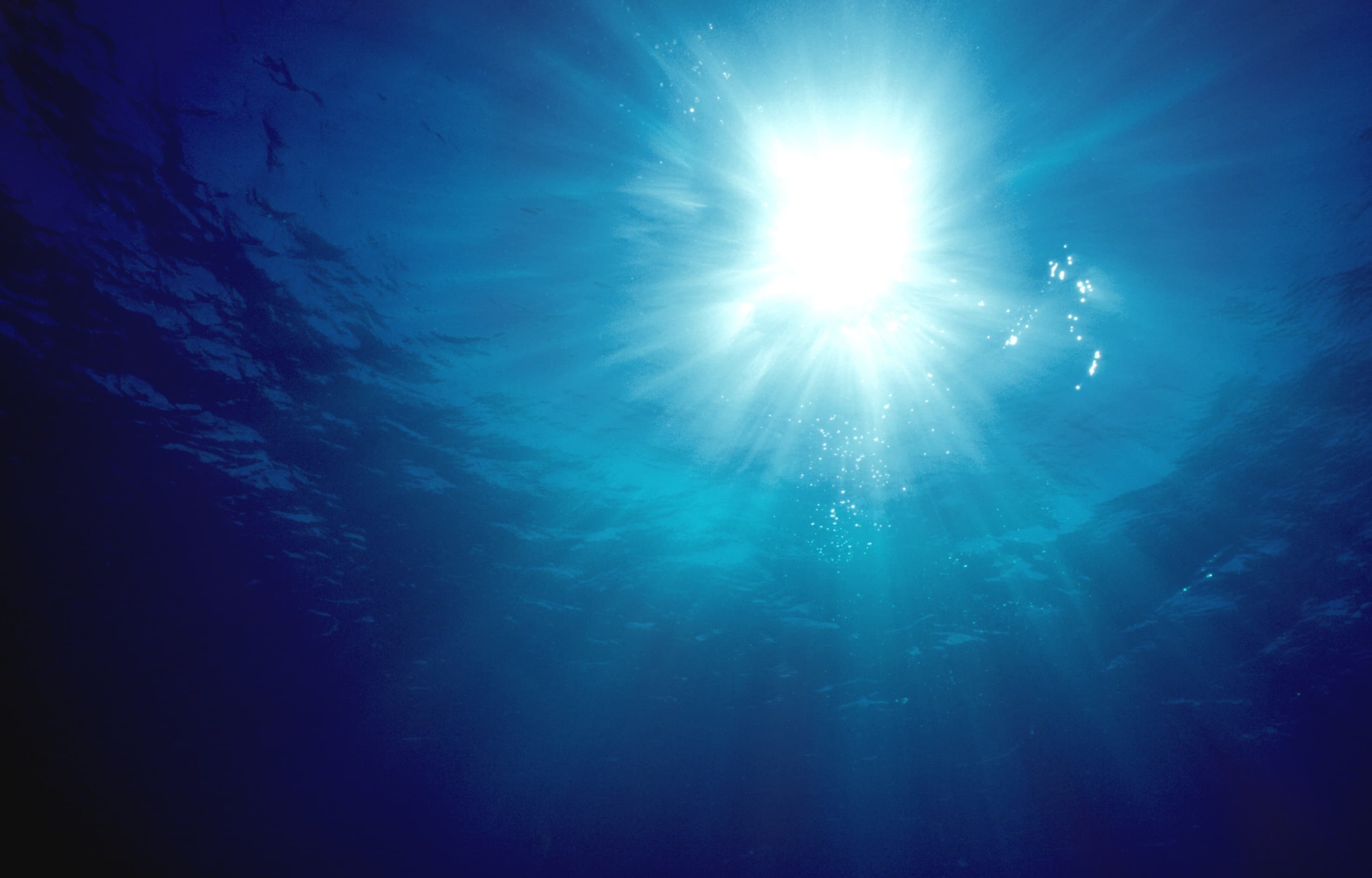 Meer Sonnenstrahlen dringen tief ins dunkle blaue Meerwasser ein