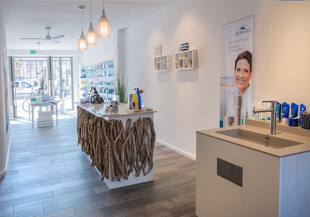 BIOMARIS Shop Travemünde Heller Verkaufsraum mit Naturholz-Theke, Pflegeprodukten und modernen Hängelampen