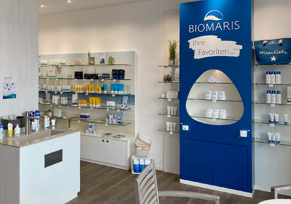 BIOMARIS Shop Scharbeutz Verkaufsfläche mit Regalen, blauer Produktwand „Ihre Favoriten“