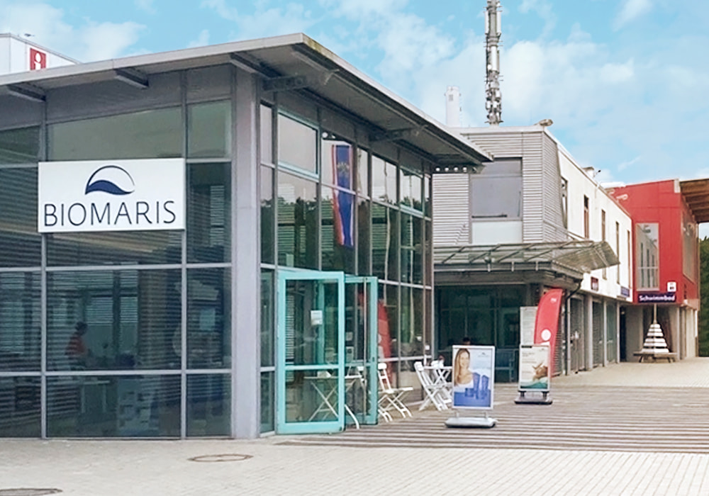 Außenansicht BIOMARIS Shops mit Glasfassade und Eingangstür in St. Peter-Ording, davor Werbeaufsteller