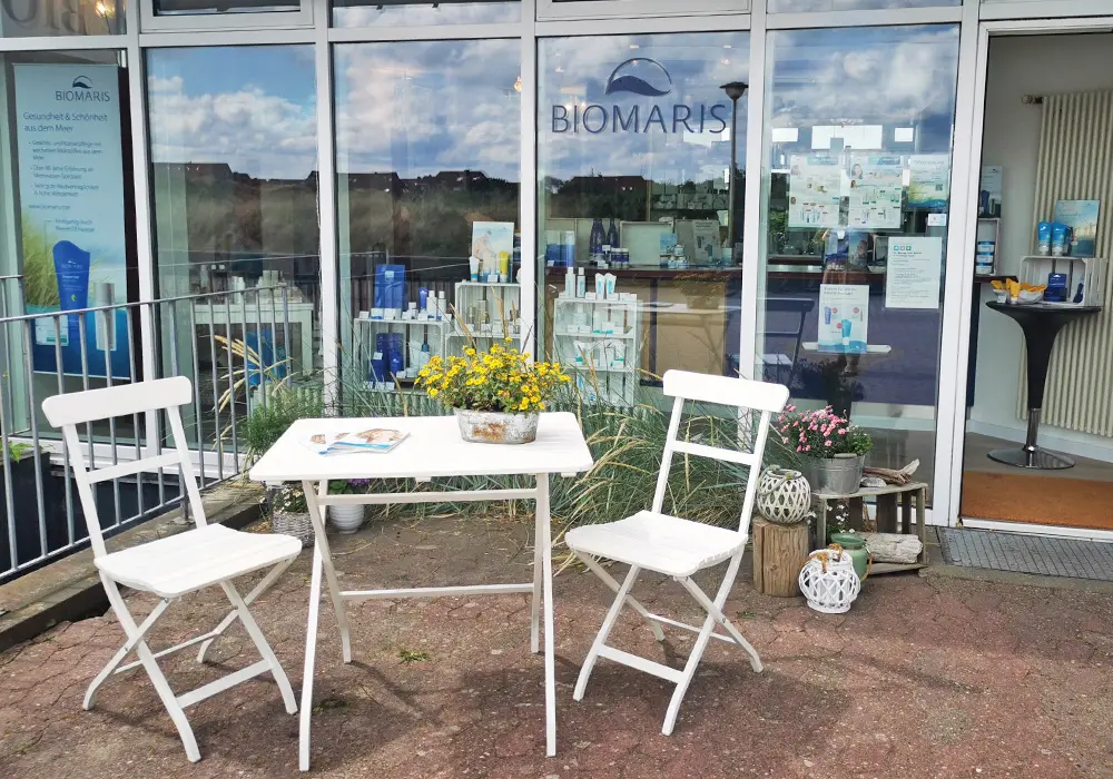 Außenbereich des BIOMARIS-Shops auf Baltrum mit weißer Sitzgruppe und Schaufensterdeko