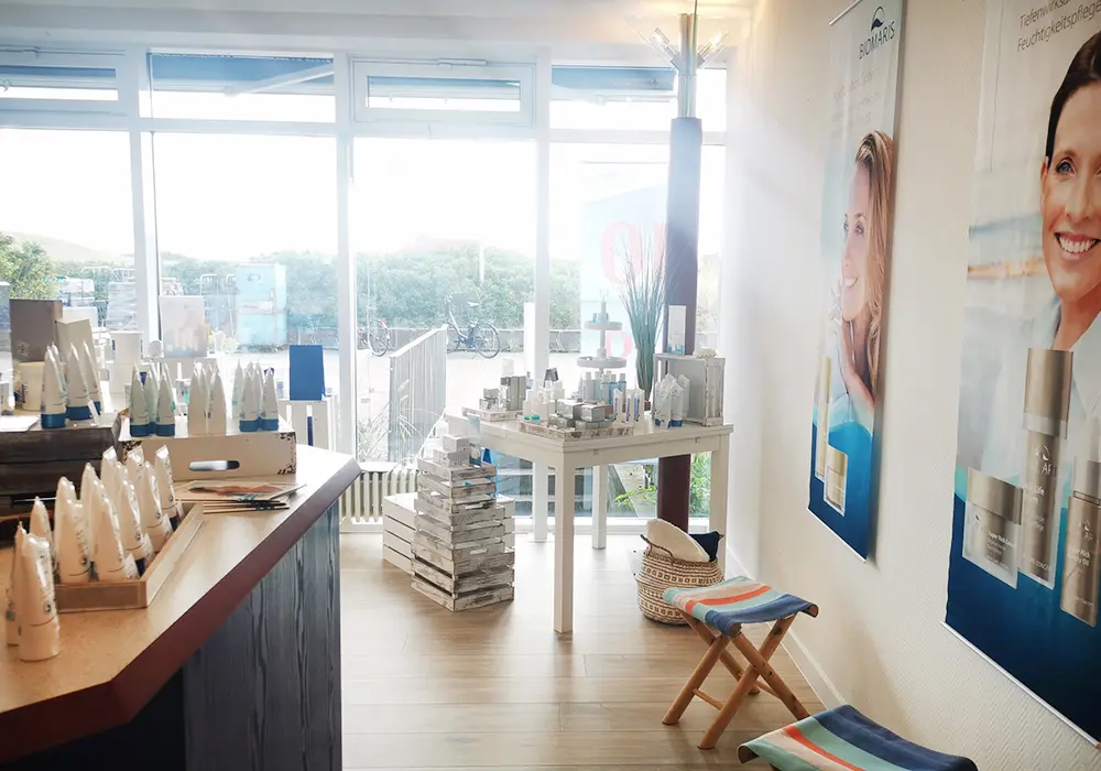 BIOMARIS Shop Baltrum BIOMARIS Shop Baltrum Verkaufsfläche mit BIOMARIS-Produkten vor großen Fenstern mit Ausblick ins Grüne