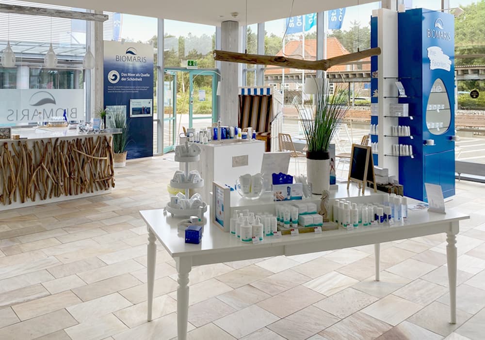 BIOMARIS Shop St. Peter-Ording Innenansicht des BIOMARIS Shops mit Produkten auf weißen Tischen, hellem Boden und dekorativer Theke im maritimen Stil