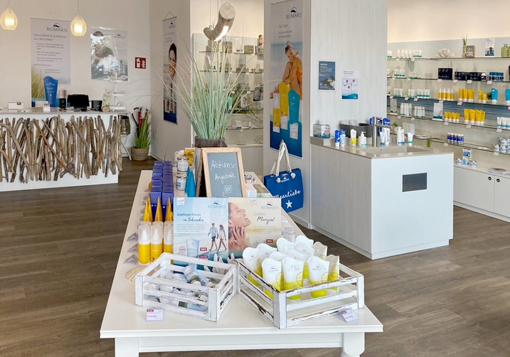 BIOMARIS Shop Scharbeutz Innenraum des BIOMARIS Shops mit Aktionsprodukten auf zentralem Tisch und Theke, im Hintergrund Verkaufsregale mit Produkten