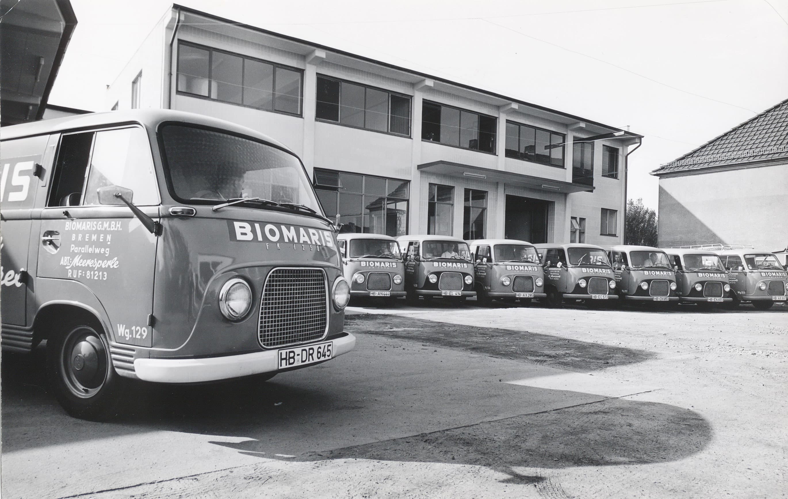 Historischer Fuhrpark von BIOMARIS vor dem Firmengebäude mit mehreren Lieferwagen